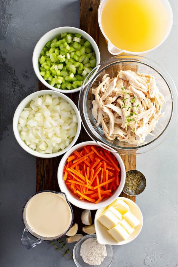 Chicken and dumpling ingredients in bowls on a cutting board. 