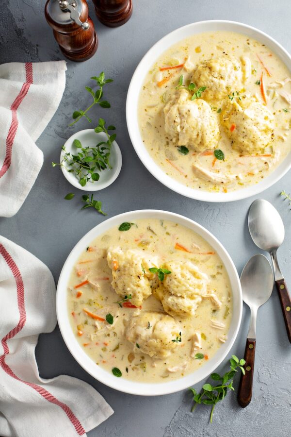 Two large bowls of homemade chicken and dumplings with three large dumplings in each bowl. 