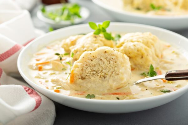 Chicken and Dumplings made from scratch with a dumpling cut in half to show the fluffy inside. 