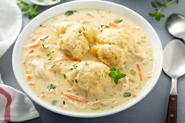 Three big homemade dumplings in a big bowl of chicken and dumplings.