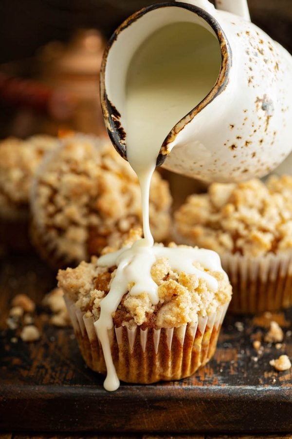 Pumpkin muffins with streusel on top and a cream cheese icing drizzle on top.