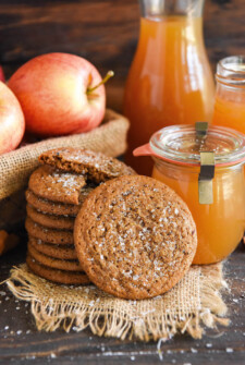 Apple Cider Cookies stacked in a tall stack with real apple cider and apples in baskets