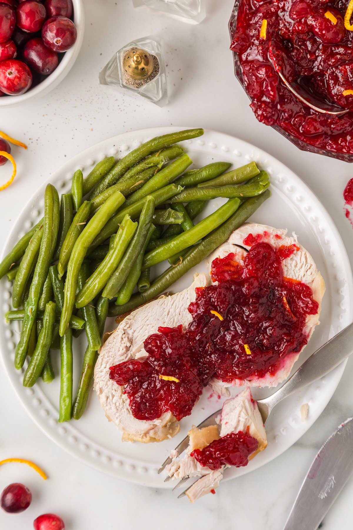 Turkey with cranberry sauce on top and green beans on the side. 