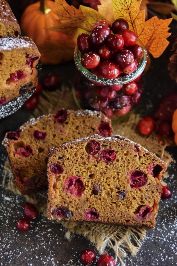 Two slices of pumpkin cranberry buttermilk bread with fresh cranberries