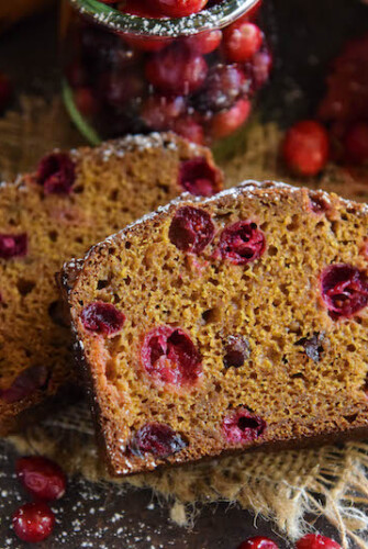 Two slices of pumpkin cranberry buttermilk bread with fresh cranberries