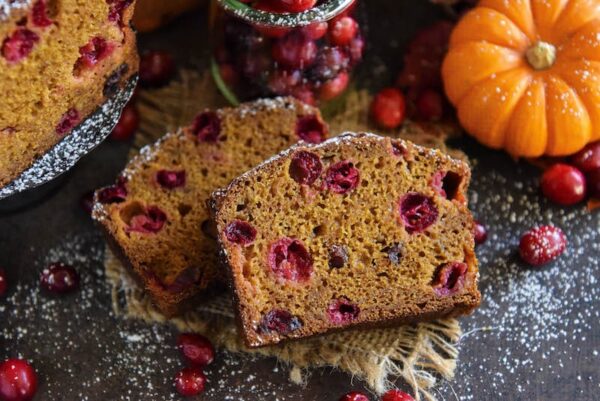 Two slices of pumpkin cranberry buttermilk bread with fresh cranberries