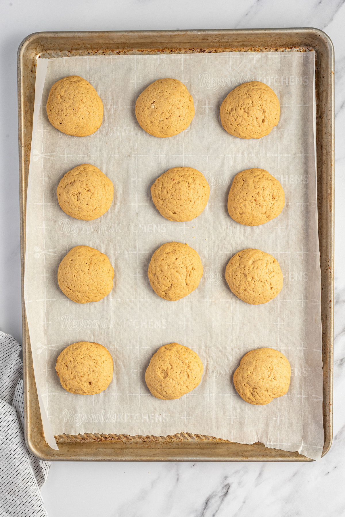A parchment-lined baking sheet of baked sweet potato cookies.