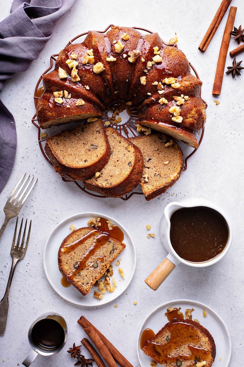 Walnut Rum Bundt Cake sliced on cake plate with a slice of rum cake on a small plate drizzled with rum sauce.