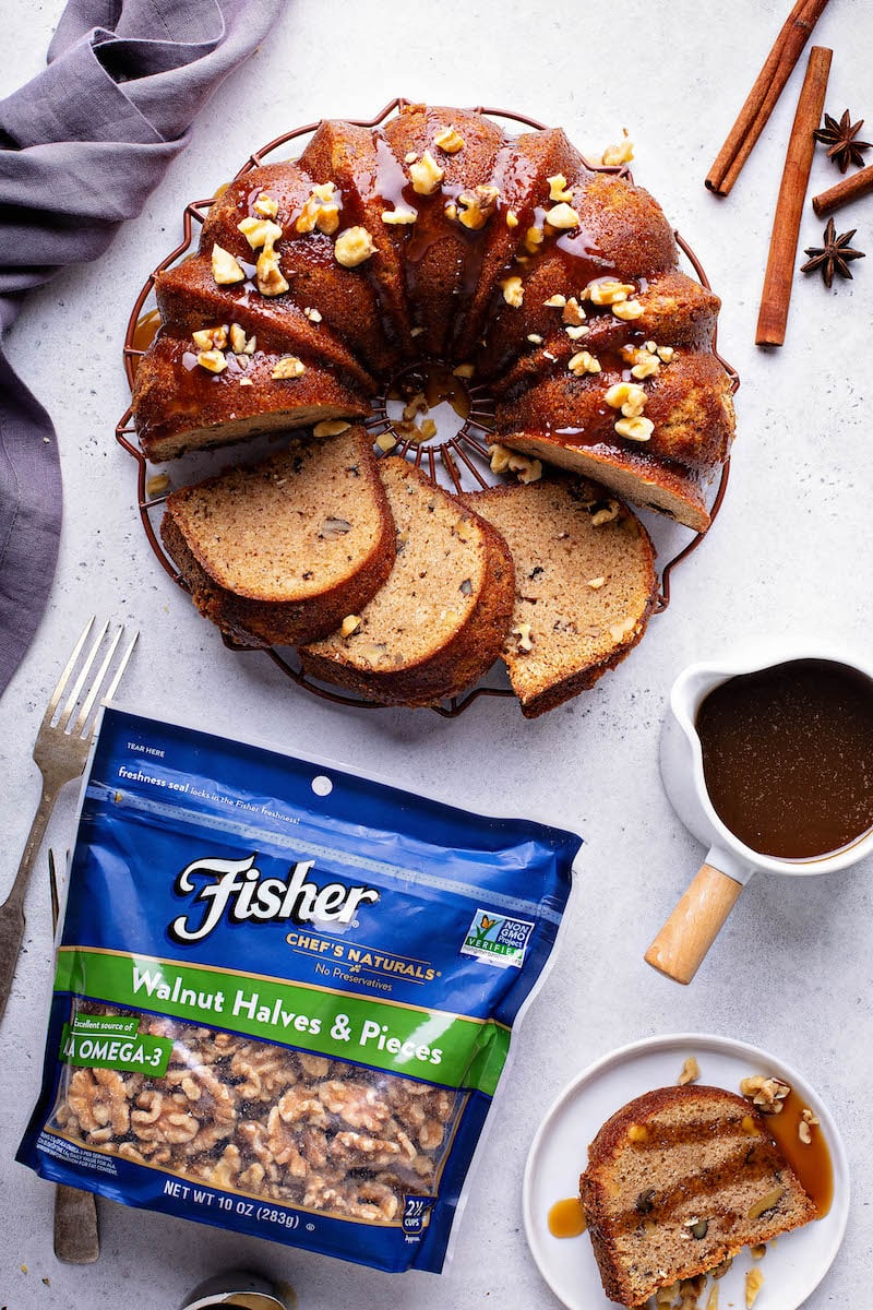 Walnut Rum Cake sliced on a cake tray with walnuts and buttery rum sauce.