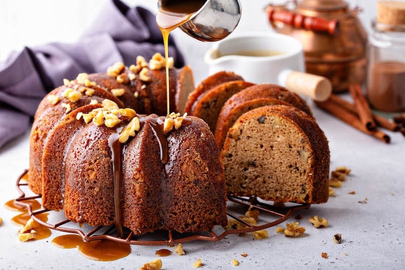 Walnut Rum cake with walnuts on top being drizzled with the rum sauce.