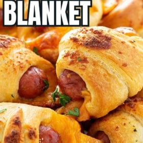 Baked pigs in a blanket with cheese are garnished with fresh herbs.