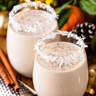 Two glasses of coquito with cinnamon on top.
