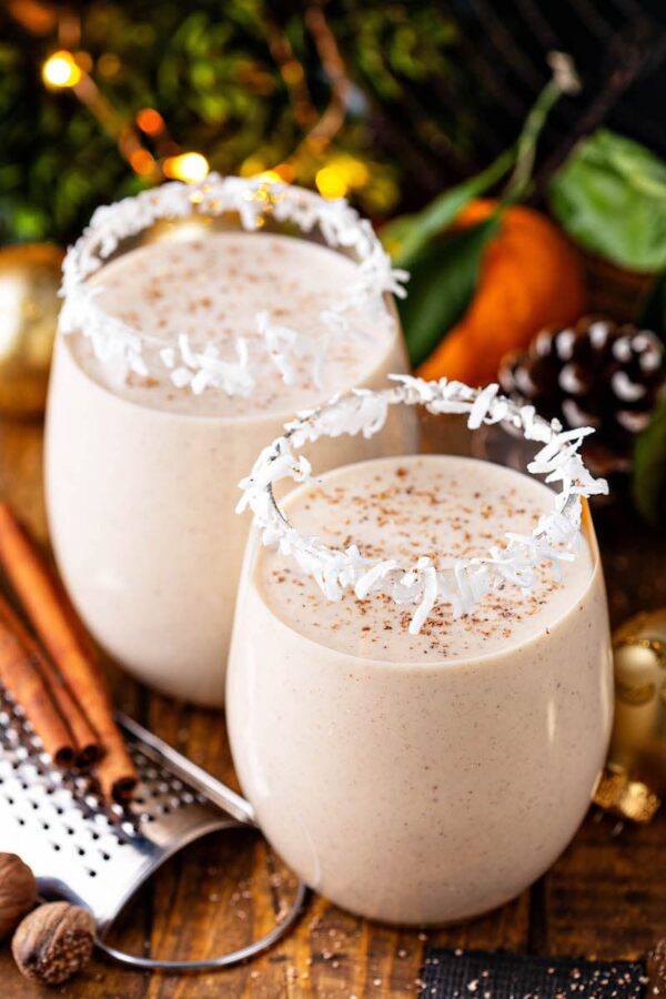 Deux verres de coquito avec de la cannelle sur le dessus.