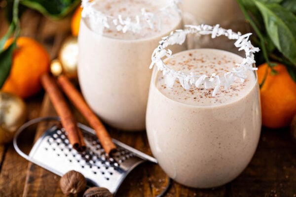 Coquito i två glas med kokosnötfälgar och mark kanel.