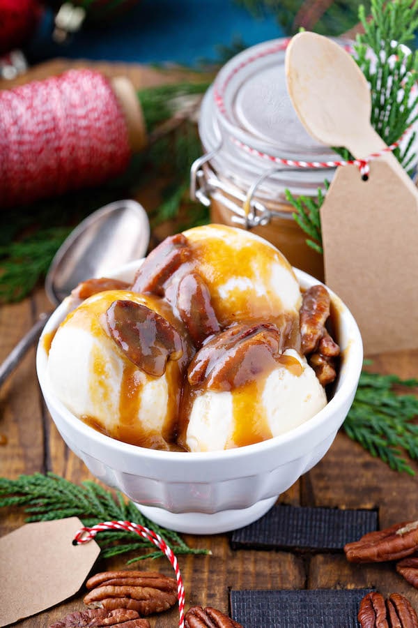 Pecan Praline Sauce in bowl poured over vanilla ice cream. 