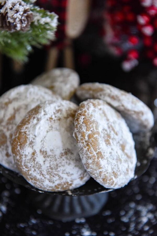 Pfeffernusse Cookies coated in powdered sugar on a cake plate