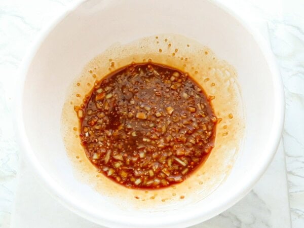 The ingredients for sesame sauce have been whisked together in a white bowl. 