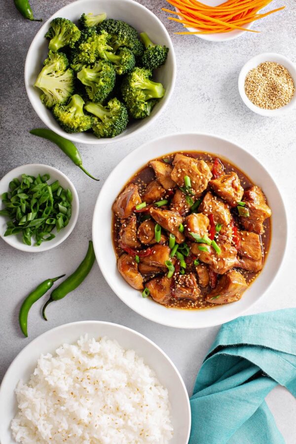 Steamed broccoli, sesame chicken straight out of the crockpot, green peppers and white rice in bowls. 