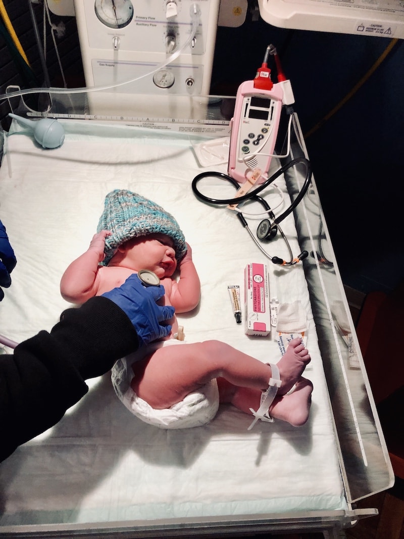 A Nurse Listening to a Newborn Baby's Heartbeat Through a Stethoscope