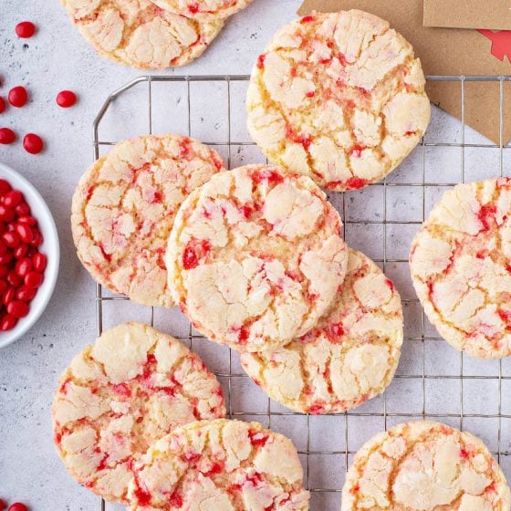 Red hot crinkle sugar cookies on a cookie sheet with red hot candies.