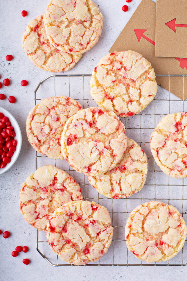 Red hot crinkle sugar cookies on a cookie sheet with red hot candies.