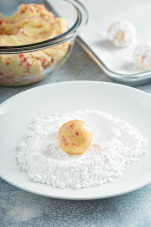 Red Hot Cookie dough being rolled in powdered sugar. 