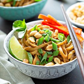 Thai peanut noodles in a bowl with chopsticks.