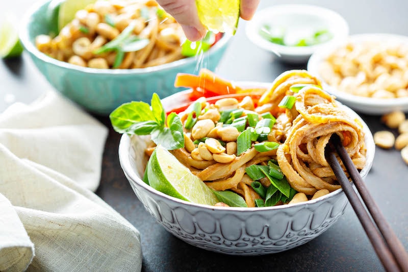 Thai peanut noodles in a bowl with toppings.