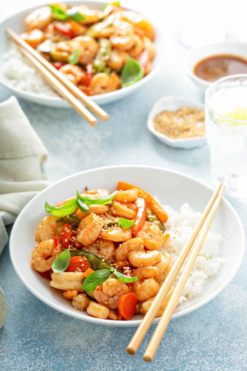 Teriyaki Shrimp StirFry in a white bowl with chopsticks and another similar bowl in the background