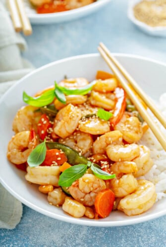 Teriyaki Shrimp StirFry in a bowl served over rice with sesame seeds sprinkled on top.