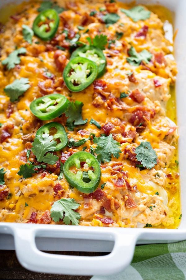 Jalapeno Popper Chicken in a baking dish topped with cheese, bacon and jalapeños.