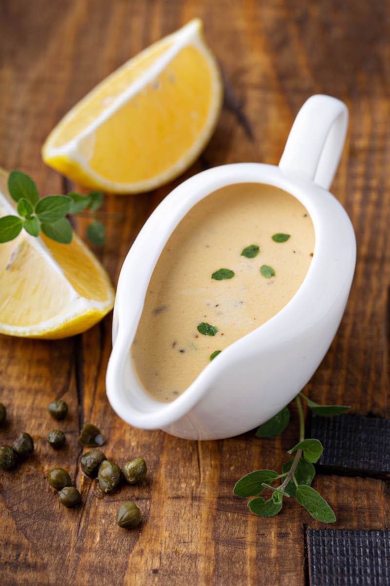 Creamy low carb lemon caper sauce in a gravy boat. 