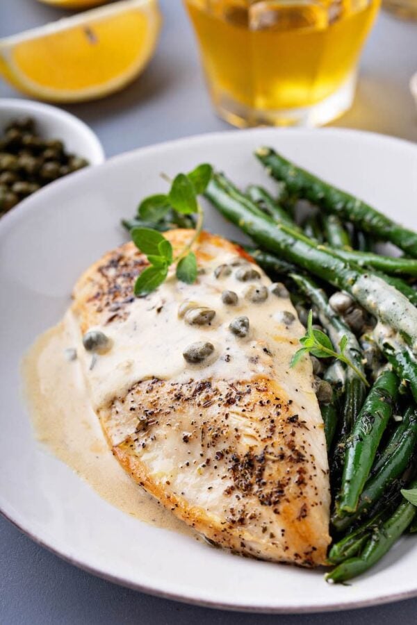 Browned chicken breasts with lemon caper sauce drizzled on top. 