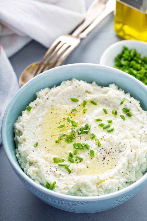 Mashed Cauliflower in a bowl with chives on top. 