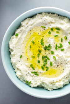Mashed Cauliflower in a bowl with chives on top.