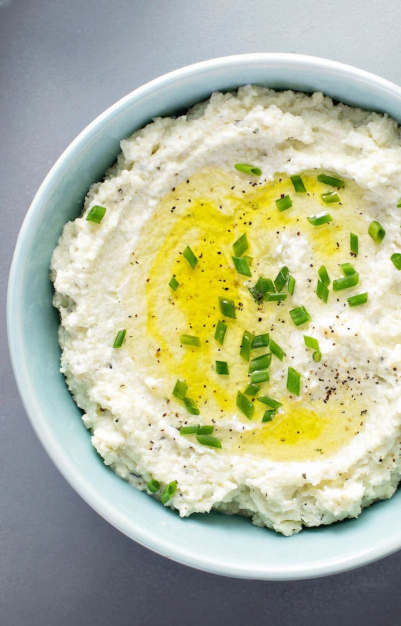 Mashed Cauliflower in a bowl with chives on top.