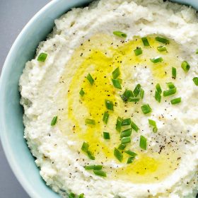 Mashed Cauliflower in a bowl with chives on top.