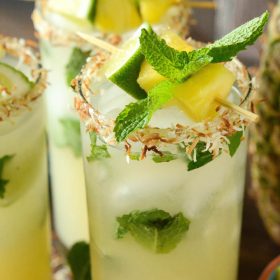Pineapple Coconut Mojitos rimmed with coconut, topped with pineapple, lime, and mint
