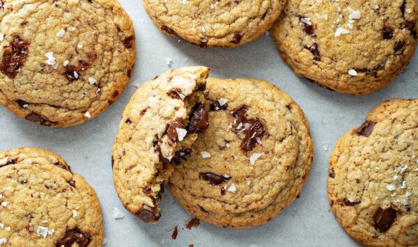 Chocolate Chunk Cookies on a cookie sheet with flaked sea salt sprinkled on top. 