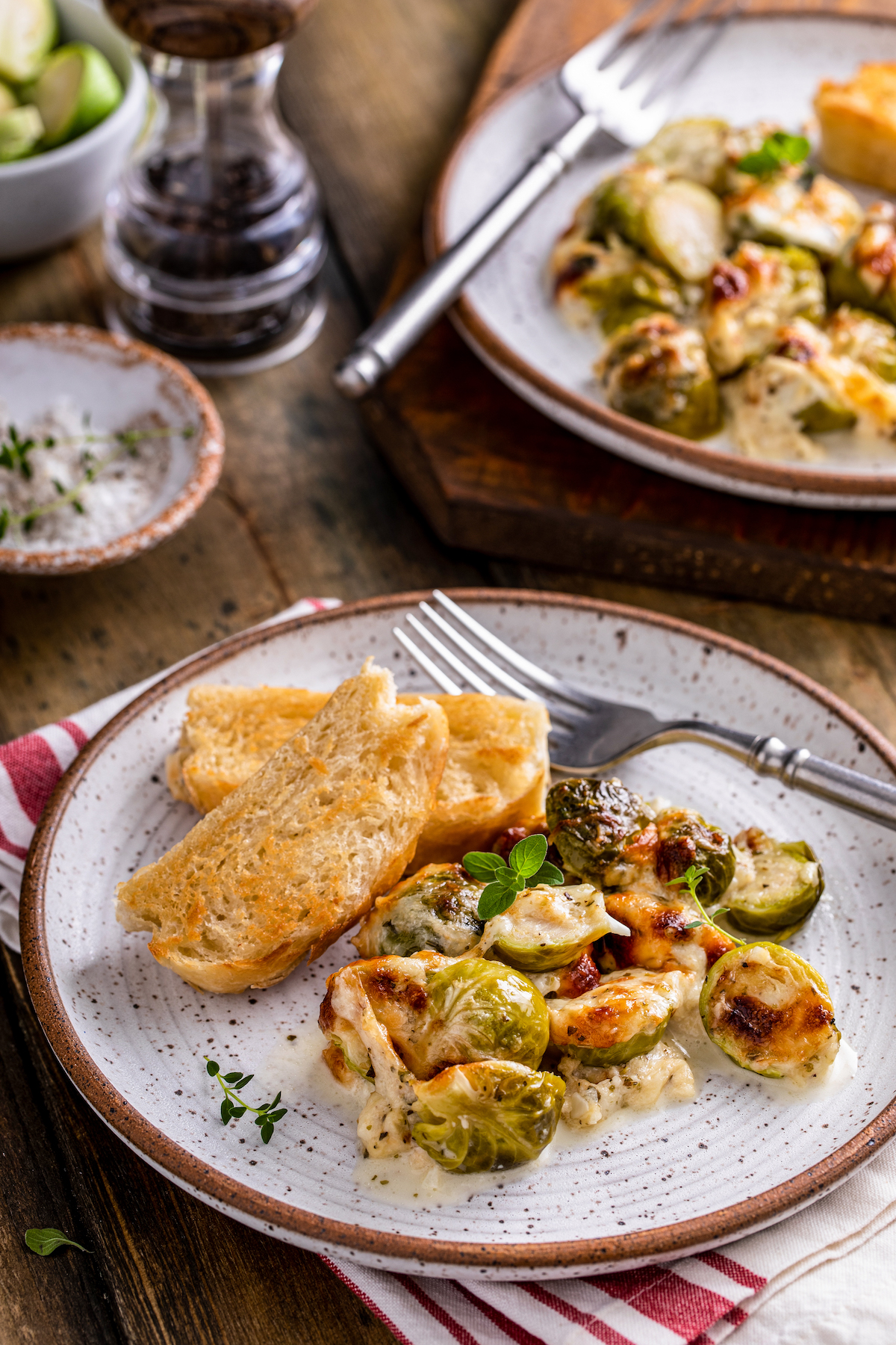 Creamy baked brussel sprouts on a plate with garlic bread.