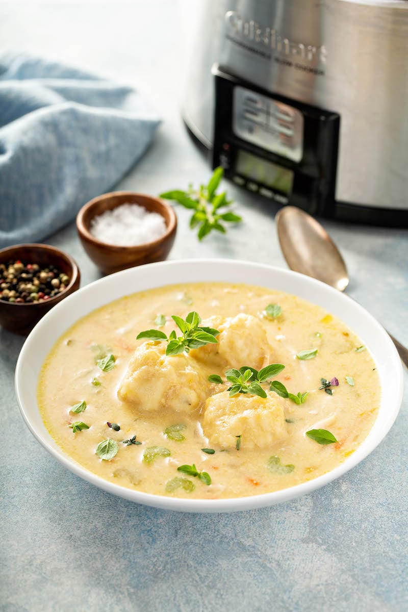 Soup in a bowl with a crockpot in the background. 