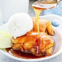 Apple dumplings being drizzled with sauce.
