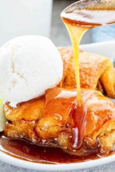 Apple dumplings being drizzled with sauce.