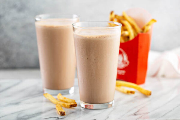 Two glasses of Wendy’s chocolate frosty and fries.