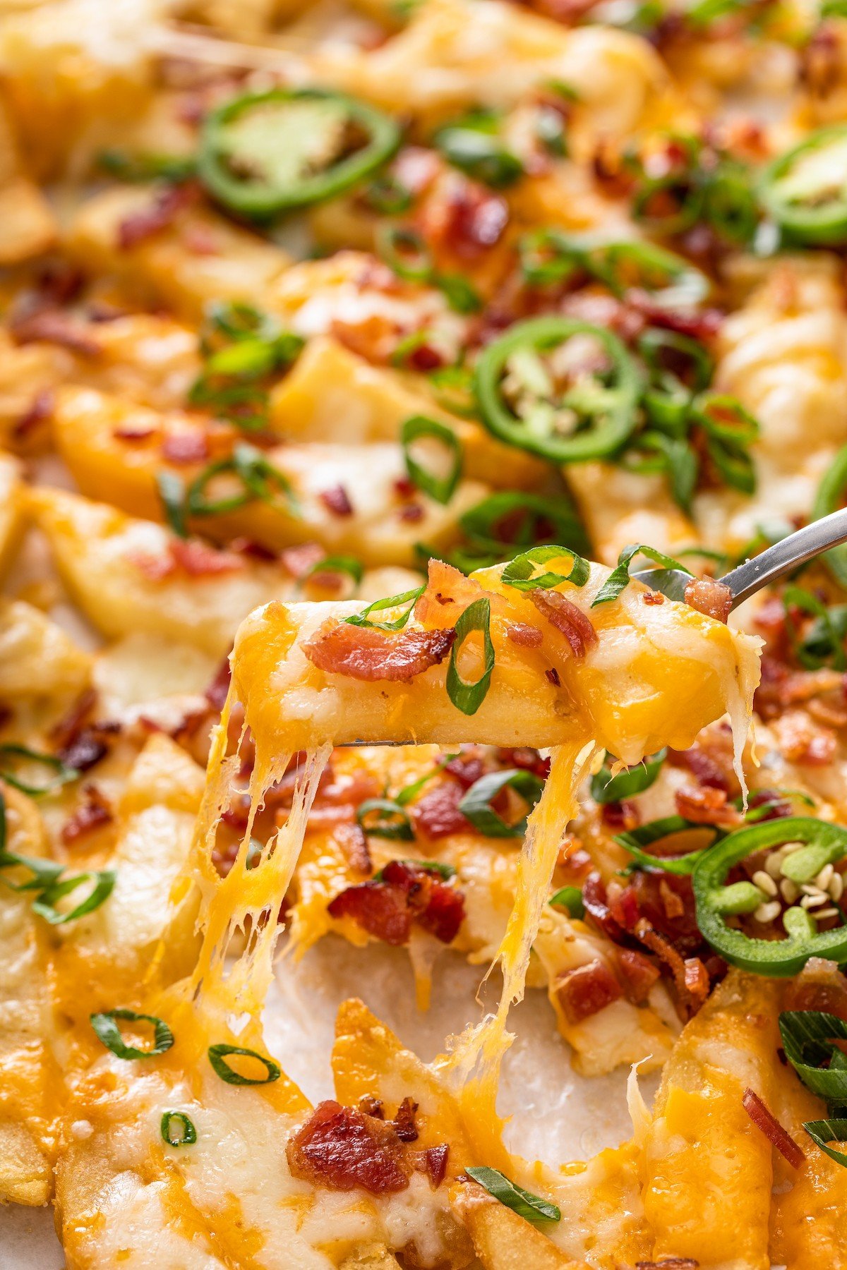 Lifting a fry off of a baking sheet, with cheese melting.