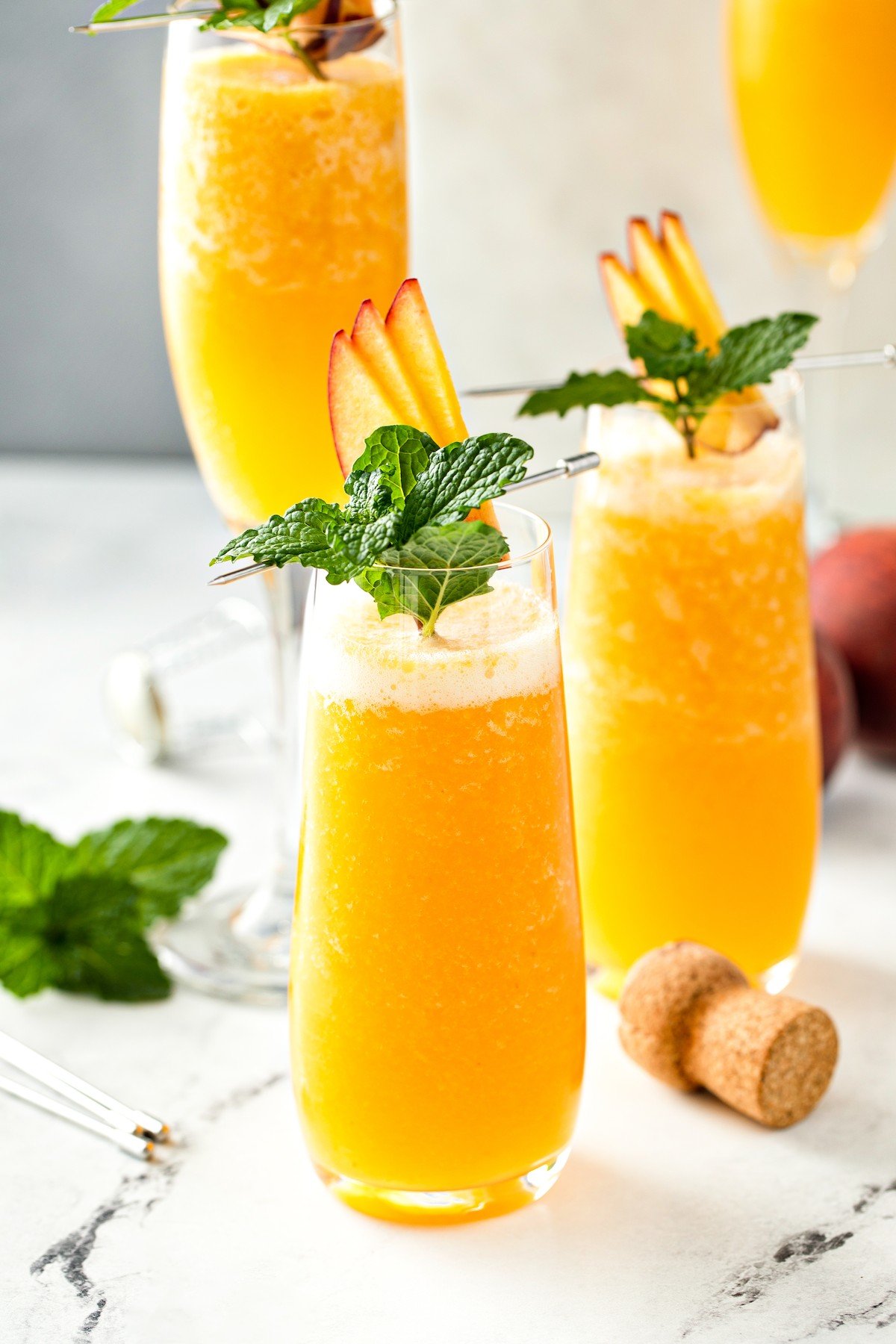 Frozen peach bellinis in glasses with mint garnish.