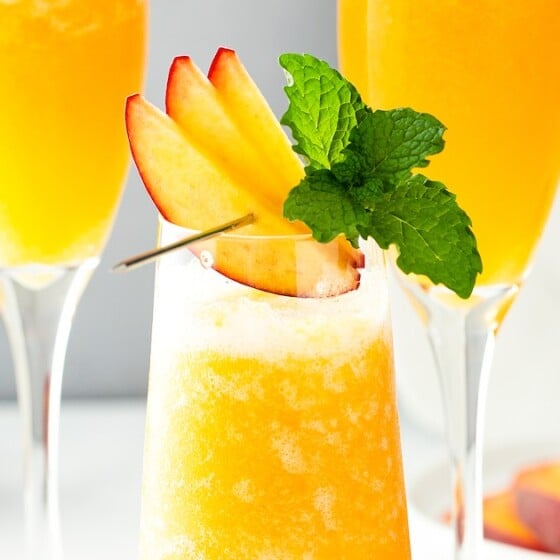Close-up of a peach cocktail with a garnish skewer balanced on the rim of the glass.