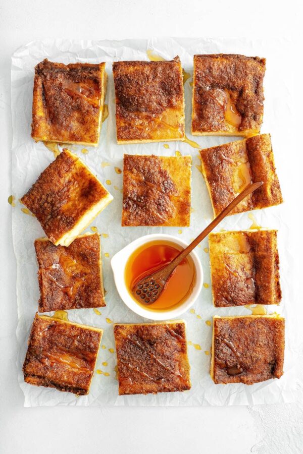 Sopapiall Cheesecake bars cut into squares on parchment paper.