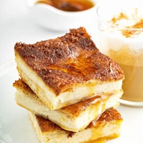 Three stacked sopapilla cheesecake bars with a drizzle of honey.