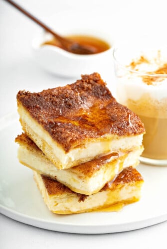 Three stacked sopapilla cheesecake bars with a drizzle of honey.